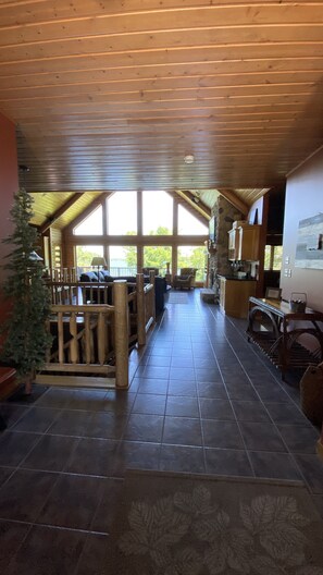 Cozy communal space with a stone fireplace, sofa, and armchairs, offering a view of the outdoors through large windows.