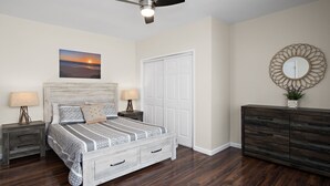 A bedroom with a bed, nightstands, a dresser, a ceiling fan, a door, and a wall-mounted mirror. - Hidden Gem Upgraded 4/2 in NW Fresno w RV Parking (Fresno)