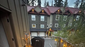 Een houten terras met een barbecue, een stoel en een hekwerk met lichtjes.