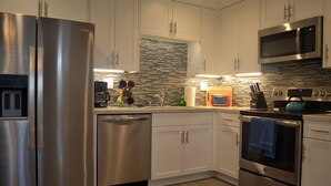 A modern kitchen with stainless steel appliances, white cabinetry, and a tiled backsplash. - Luxury, Ground Floor Studio #4 just 167 steps to the Best Beach in San Diego! (San Diego)