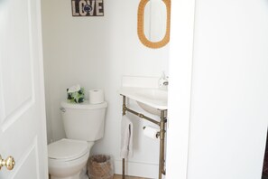 A bathroom with a toilet, a sink, and a mirror. - Our Guest House (State College)