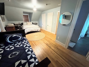 A bedroom with a bed, a bedside table, a mirror, and a door. - Our Guest House (State College)