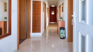 A hallway with wooden doors, a tiled floor, and a trash bin. - Apartment Laura by Interhome (Pula/Galižana)