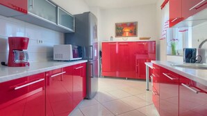 A modern kitchen with red cabinets, a white countertop, and a microwave. - Apartment Laura by Interhome (Pula/Galižana)