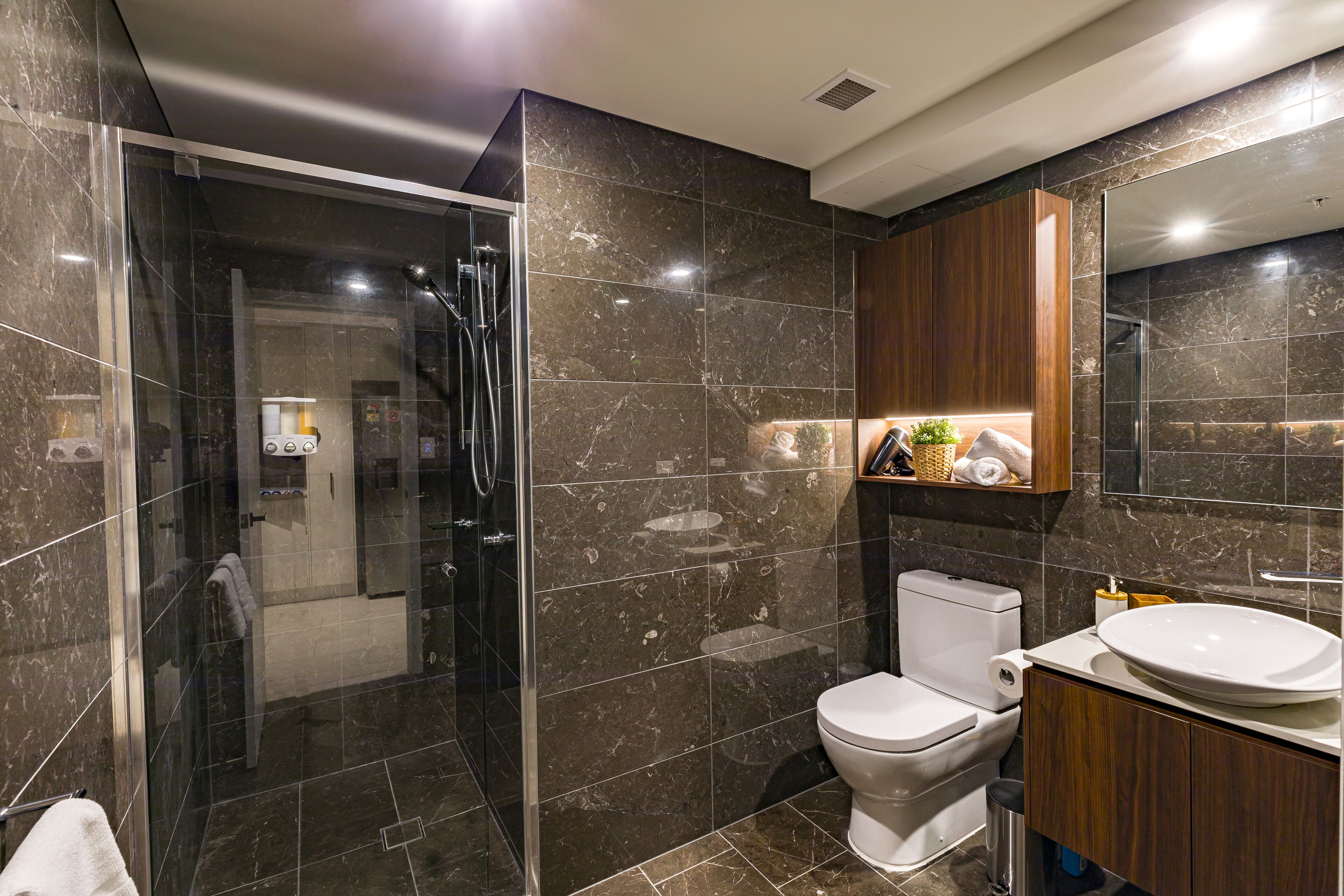 Une salle de bain moderne avec une douche à parois de verre, des toilettes et un meuble-lavabo avec un évier.