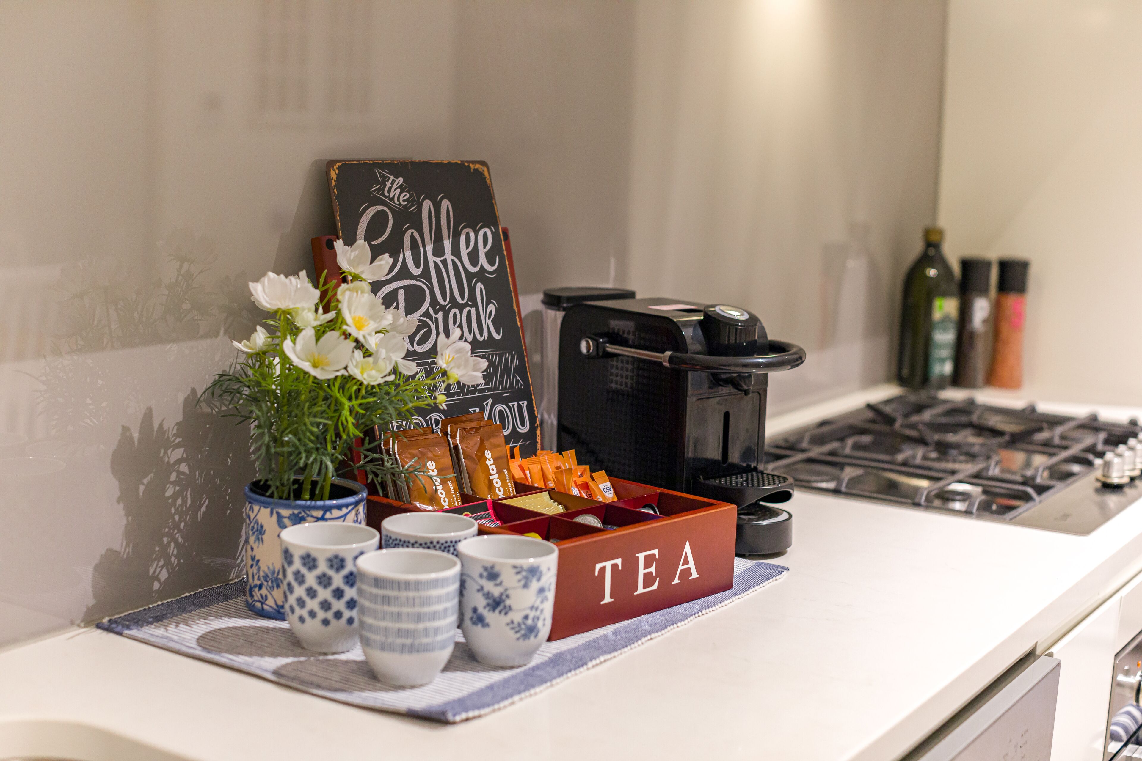 Un comptoir de cuisine avec une machine à café, une boîte à thé et des objets décoratifs.