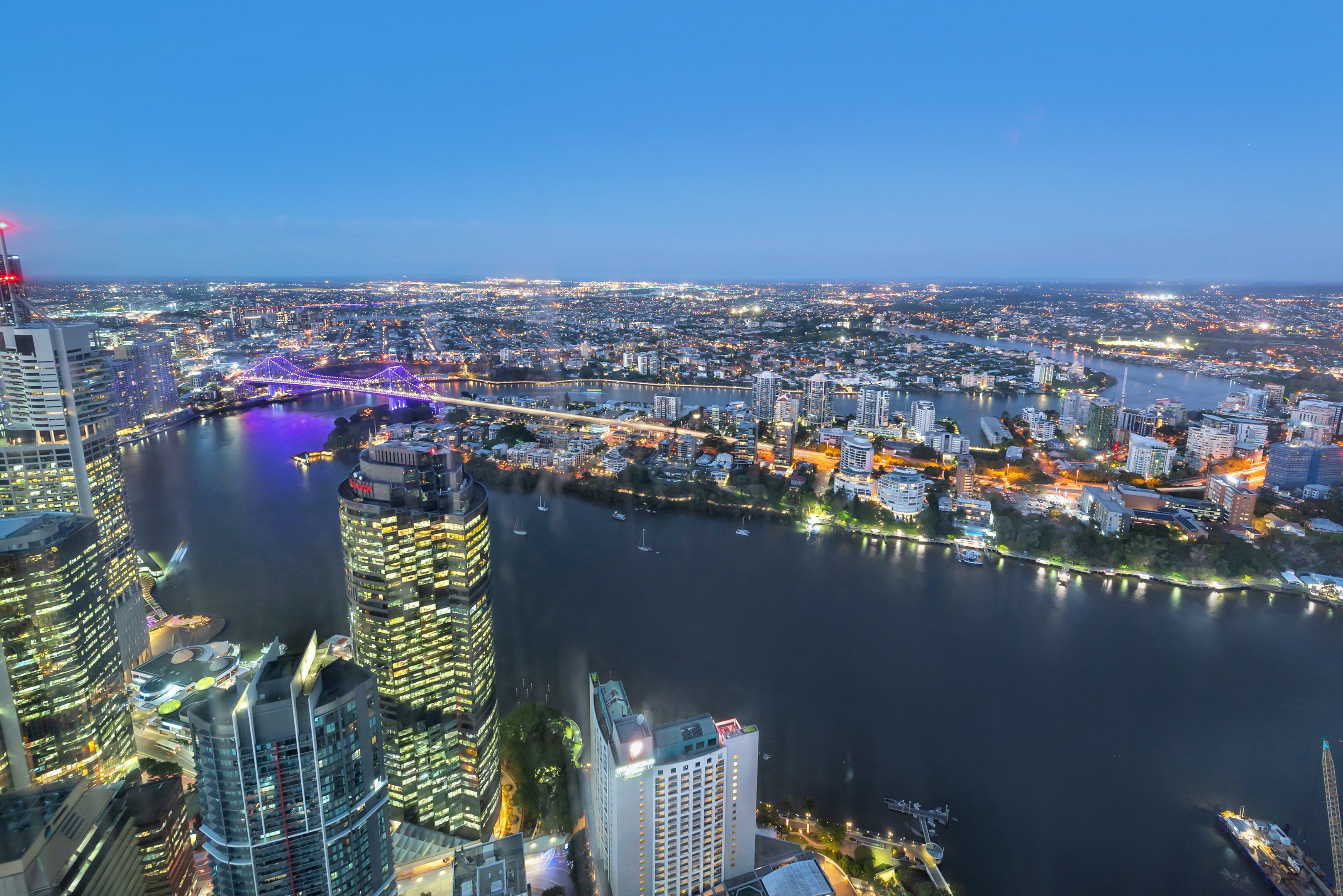 A cityscape with a prominent bridge, high-rise buildings, and a river.
