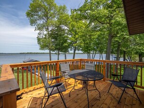 A wooden deck with a table and chairs overlooking a lake. - Lake home, 3 bd 3 bath, 2 car garage deck, dock, Video game, foosball, quiet bay (Isle)