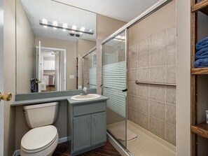 A modern bathroom with a toilet, sink, and shower area. - Lake home, 3 bd 3 bath, 2 car garage deck, dock, Video game, foosball, quiet bay (Isle)