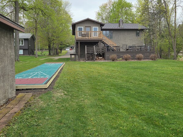 A residential property with a two-story house, a deck, and a shuffleboard court. - Lake home, 3 bd 3 bath, 2 car garage deck, dock, Video game, foosball, quiet bay (Isle)