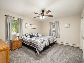 A bedroom with a bed, a nightstand, a ceiling fan, and two windows with curtains. - Lake home, 3 bd 3 bath, 2 car garage deck, dock, Video game, foosball, quiet bay (Isle)
