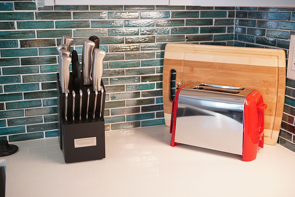 A kitchen with a knife block, toaster, and wooden cutting board.