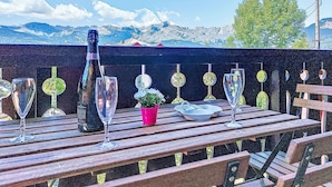 A wooden deck with a bottle of champagne, several glasses, and a small potted plant.
