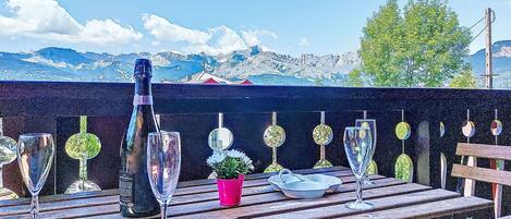 A wooden deck with a bottle of champagne, several glasses, and a small potted plant.