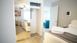 Un dormitorio con cama, armario, espejo y ventilador de techo.