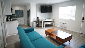 Un salón moderno con un sofá color turquesa, una mesa de centro de madera y un televisor montado en la pared.