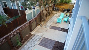 Un patio trasero con zona de estar, mobiliario exterior, cerca de madera y una bicicleta.