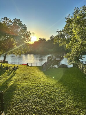 A grassy park area with a wooden deck and a view of a lake.