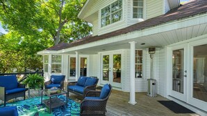 A covered outdoor area with wicker furniture, a patterned rug, and a trash can. - Lake It Easy...5BR Waterfront Home, Dock, Deck and Game Area (New Braunfels)