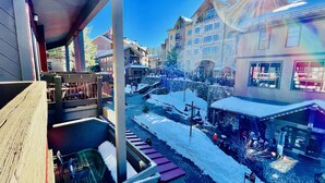 A snow-covered town square with buildings, a wooden deck, and a stone bridge. - SPECIAL DISCOUNT on Penthouse in NorthstarVillage,a wonderful getaway (Truckee)