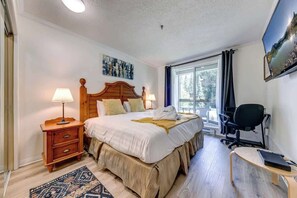 Ein Schlafzimmer mit einem Bett, Nachttischen, einem Schreibtisch, einem Sessel und einem Fernseher.