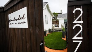 A wooden gate with a sign reading "Peachcluded" and a house number "227".