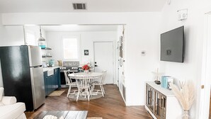 A modern kitchen with white cabinets, a black refrigerator, and a dining area with a white table and chairs.
