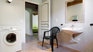 Een badkamer met een wasmachine, een wastafel en een stoel.