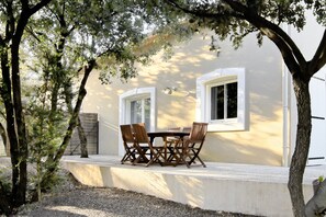 An outdoor seating area with a table and chairs, a concrete bench, and a tree.