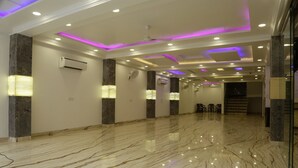 A spacious lobby with marble flooring, recessed lighting, and air conditioning units.