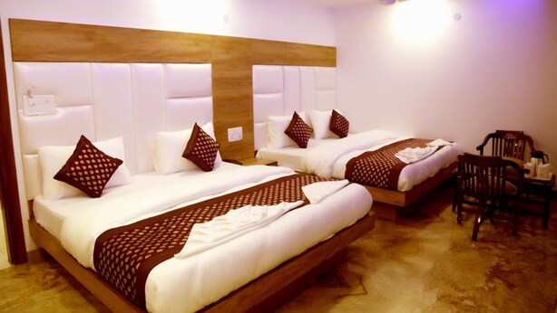 A hotel room with two beds, a wooden headboard, white bedding, and a wooden floor.