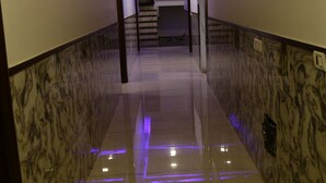 A hallway with marble walls and a reflective floor, leading to a staircase.