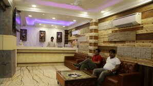 A lobby with a reception desk, leather couches, a marble floor, and an air conditioning unit on the wall.