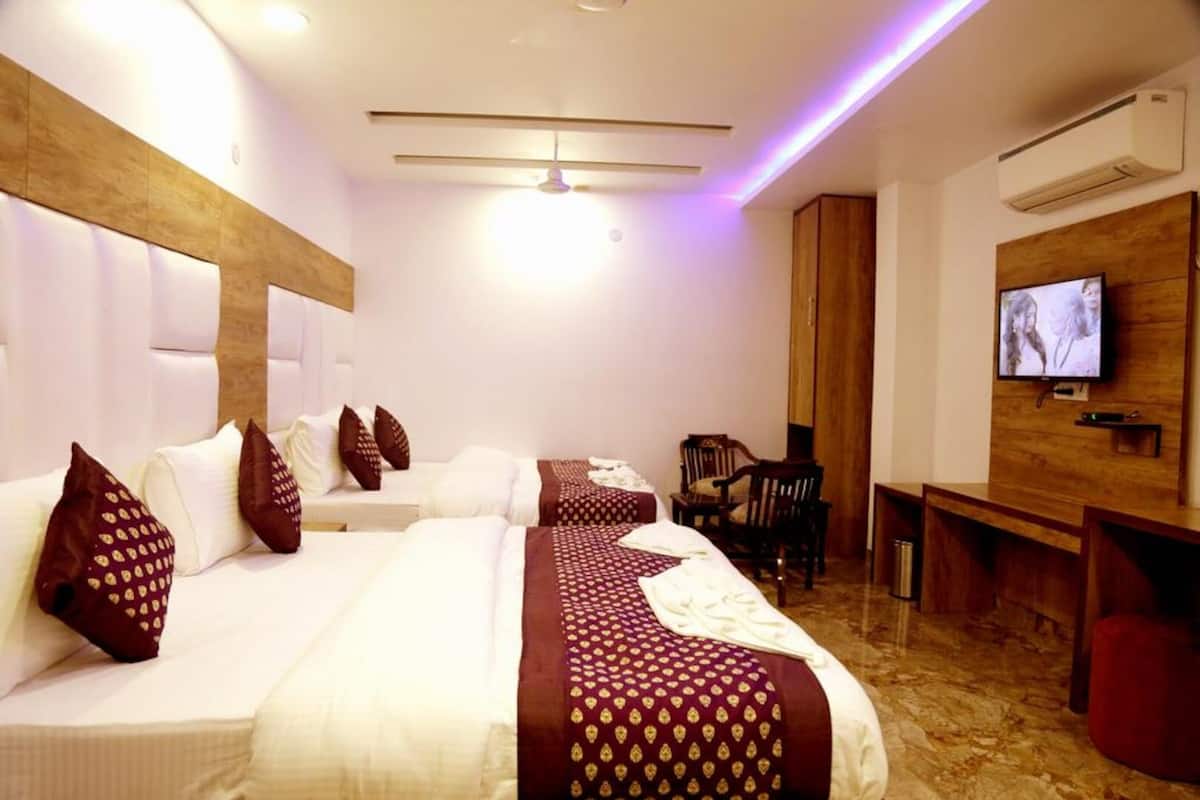 Habitación de hotel con dos camas, televisión, aparador de madera y escritorio.