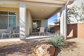Relax on the covered patio with a seating area featuring two chairs and a table.