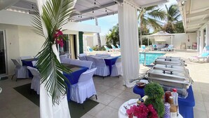 Un espace extérieur abrité comprenant une piscine, des chaises longues et une table de buffet.