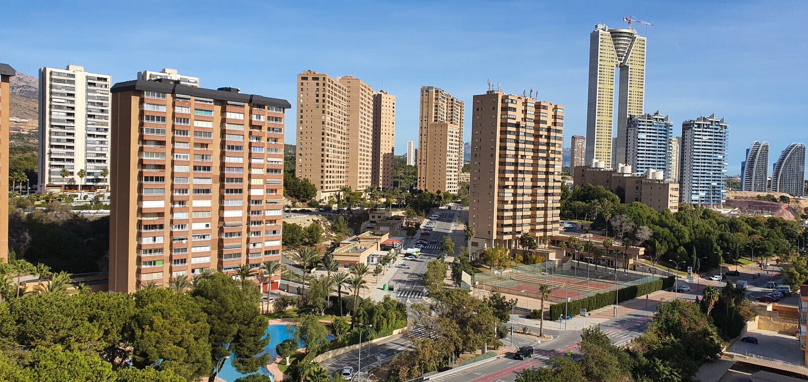 A high-rise residential area with multiple apartment buildings, a parking lot, and a small pool area surrounded by greenery.