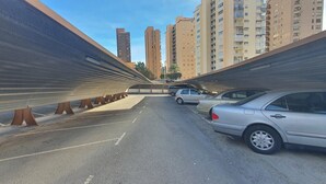 Ein Parkplatz mit Autos und einem Fußweg unter einer Brücke.