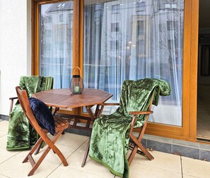 A wooden table with a round glass top, surrounded by four chairs with green velvet upholstery.