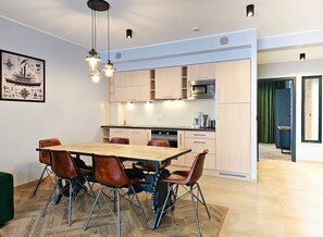 A modern kitchen with wooden cabinets, a stainless steel microwave, and a dining area with a wooden table and leather chairs.