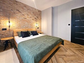 A bedroom with a brick wall, a wooden bed frame, and a black door.