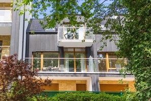 Un bâtiment moderne à deux étages, doté d’un balcon, de grandes fenêtres et d’un toit plat.