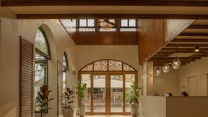 A hotel lobby with a wooden ceiling, large arched entrance, potted plants, and hanging pendant lights. - The Motifs Eco Hotel (Chanthaburi)