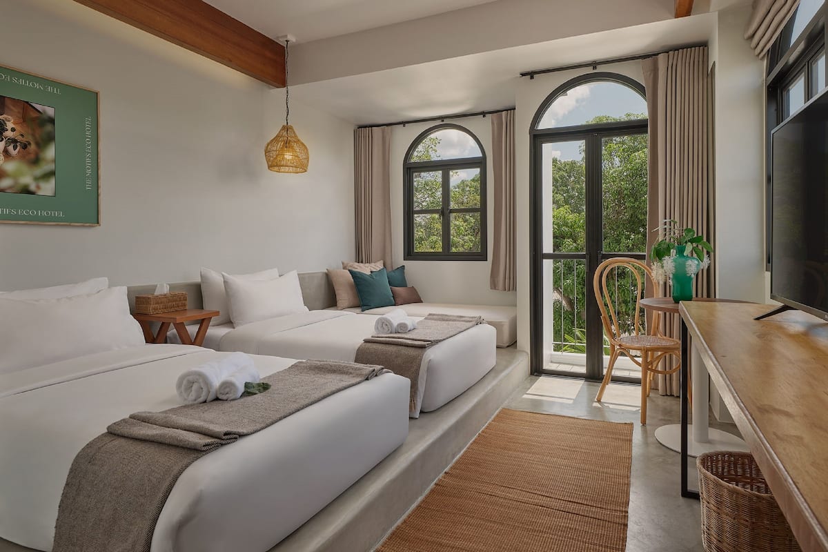 Une chambre d’hôtel avec deux lits, une télévision, un coin repas et une vue sur la verdure.