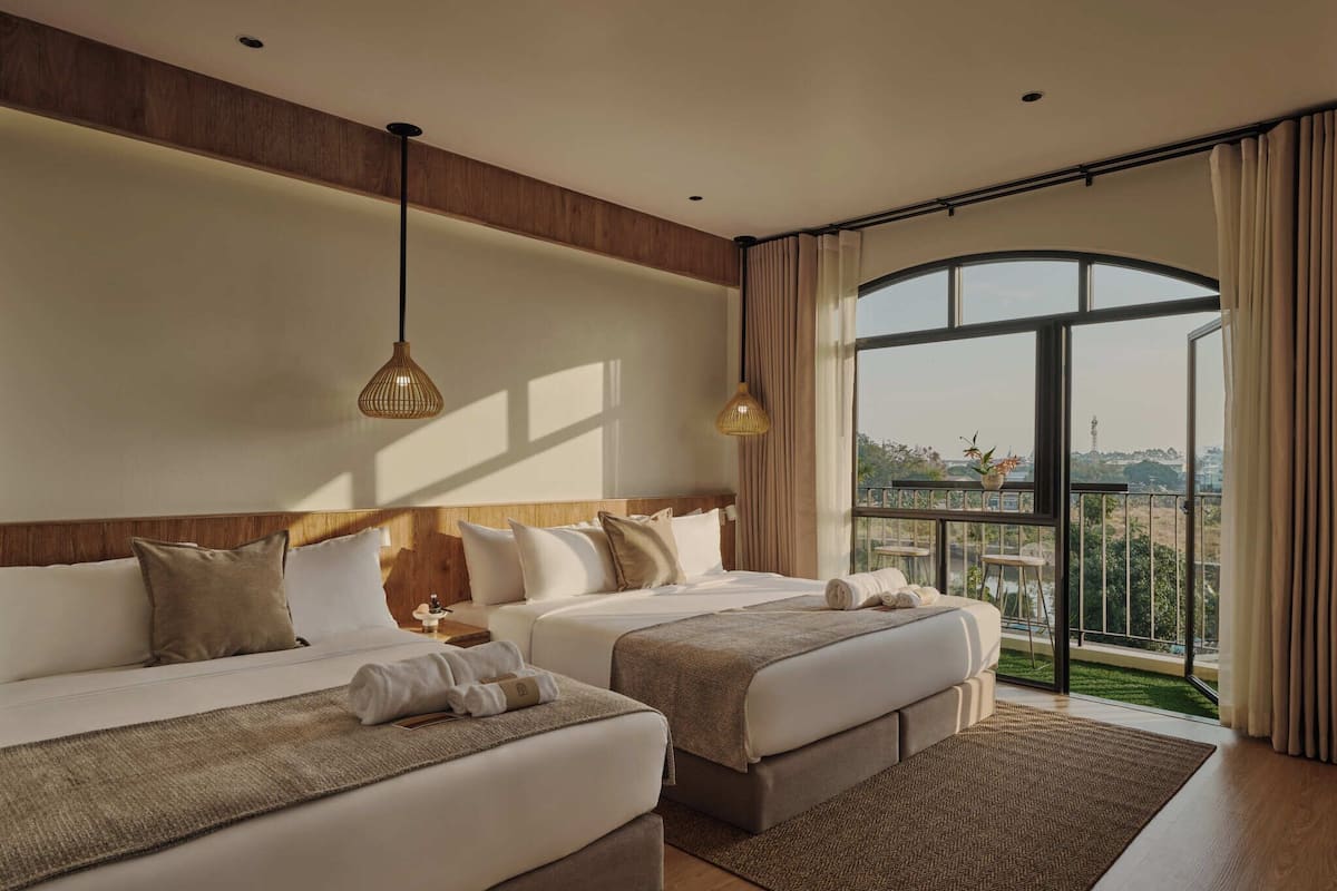 Une chambre d’hôtel avec deux lits, une grande fenêtre donnant sur un beau paysage et un plafond en bois.
