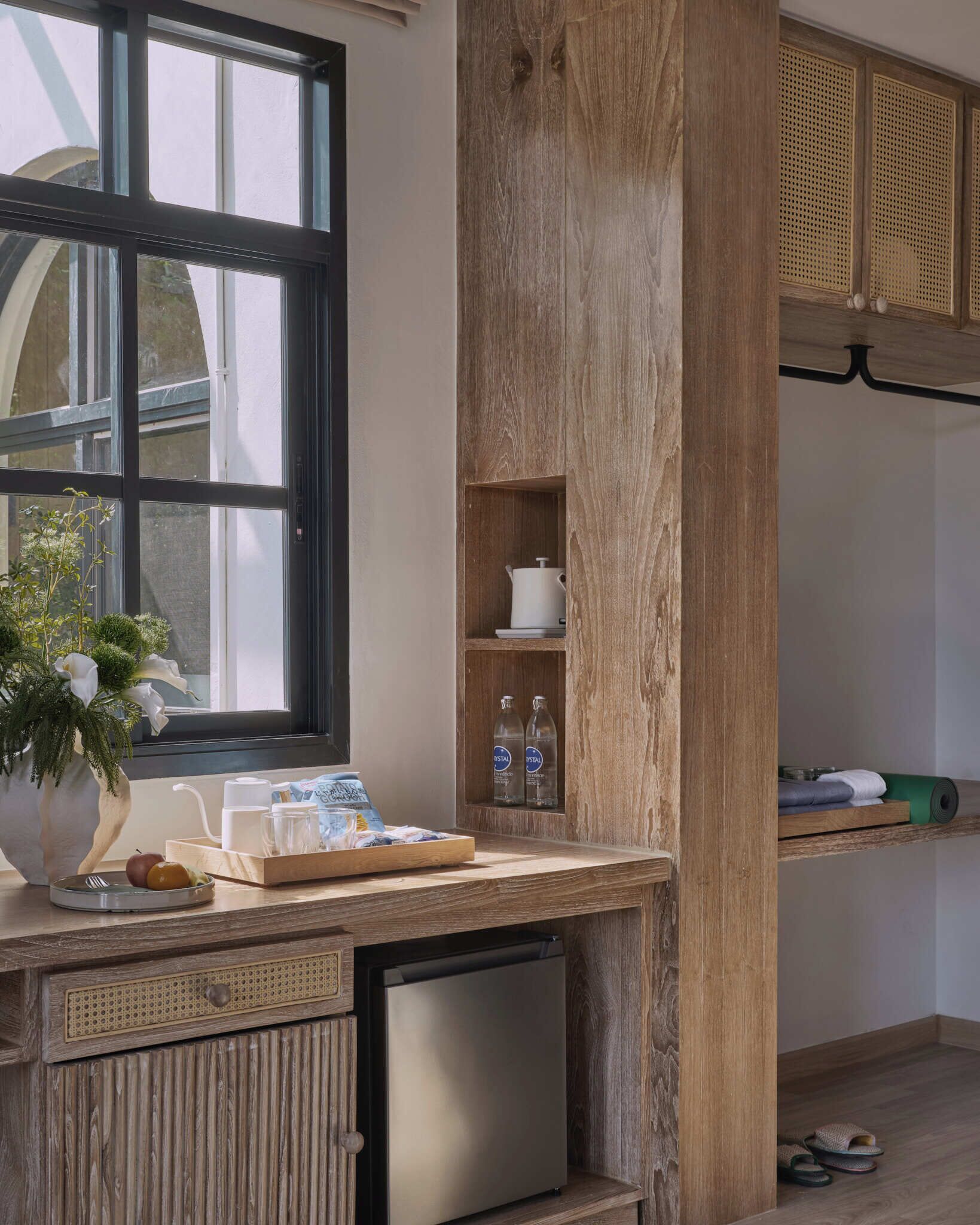 A kitchen with a built-in refrigerator, wooden cabinets, a window, and a small sink.