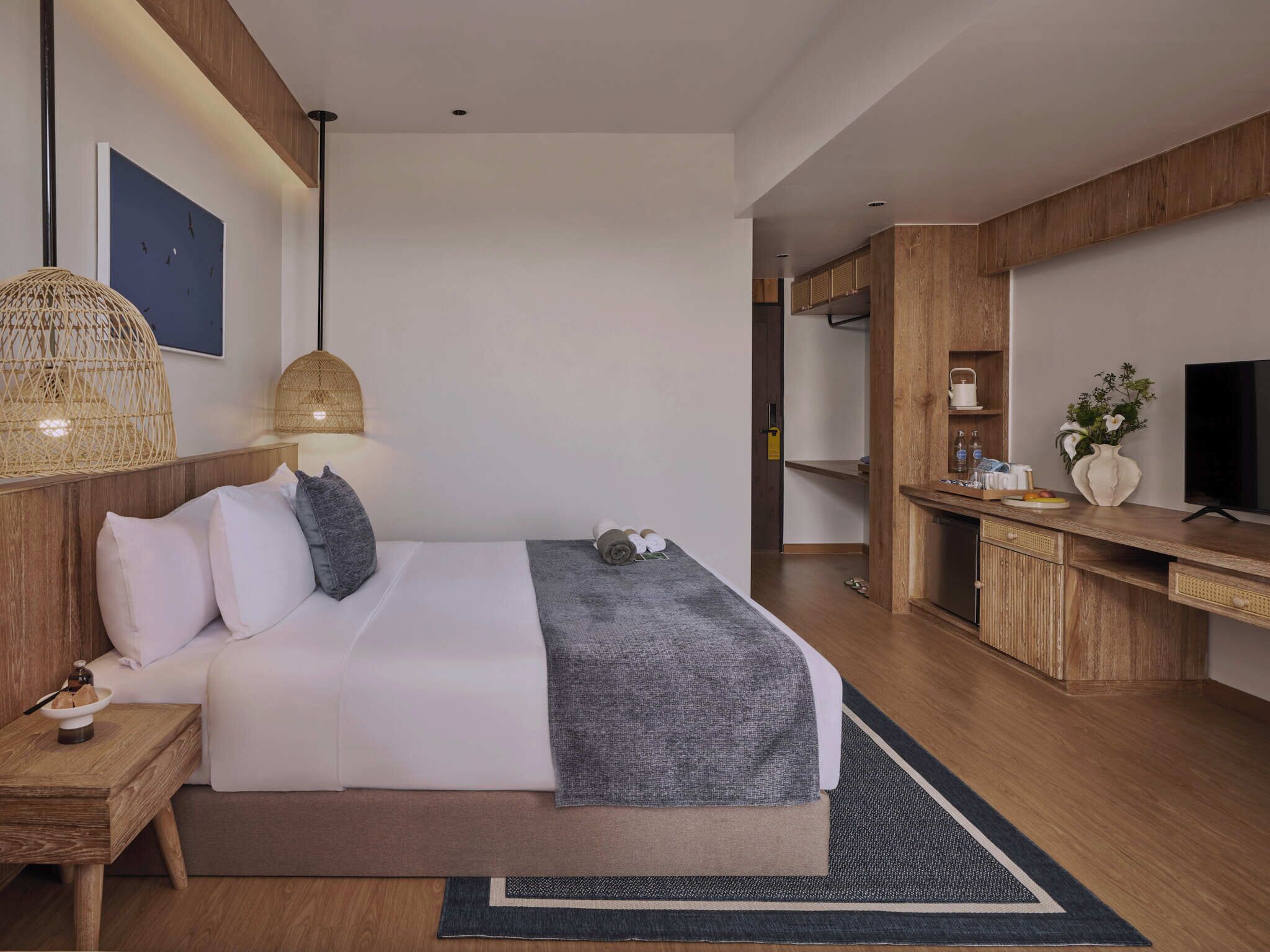 A modern hotel room with a large bed, bedside tables, a desk, and a television.