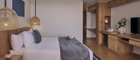 A modern hotel room with a large bed, bedside tables, a desk, and a television.