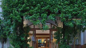 A traditional Japanese-style entrance with a wooden archway, a brick pathway leading to a seating area, and lush greenery surrounding the space. - The Motifs Eco Hotel (Chanthaburi)