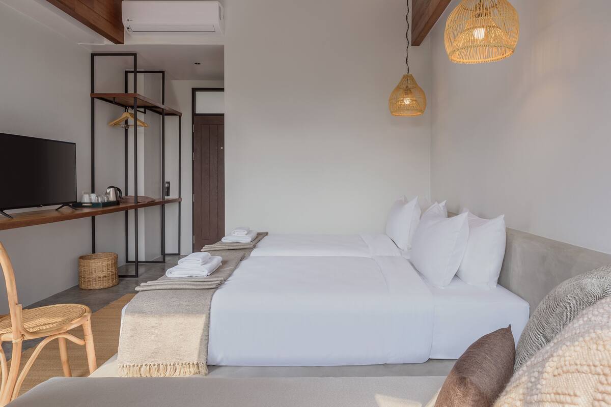 Une chambre d’hôtel moderne équipée d’un lit, d’une télévision, d’un bureau et d’un luminaire suspendu.
